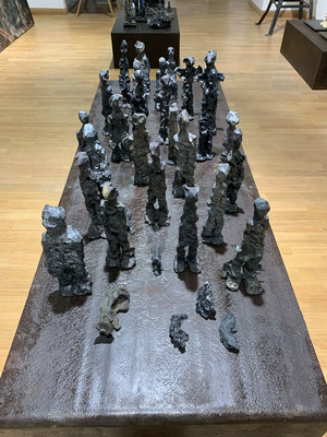 Wilhelm Moser - Vagabonds de l'âme, 2021 - Tableau de 33 figurines en terre cuite sur table industrielle en acier (5 à 29 cm)